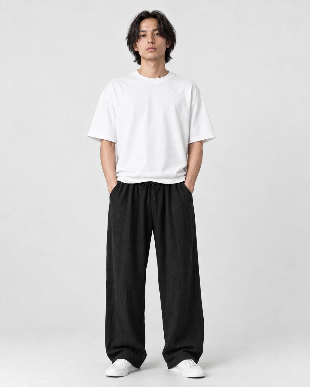 Model wearing the black wide-leg linen pants with a white tee and white sneakers, front view