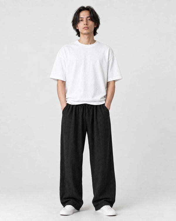 Model wearing the black wide-leg linen pants with a white tee and white sneakers, front view