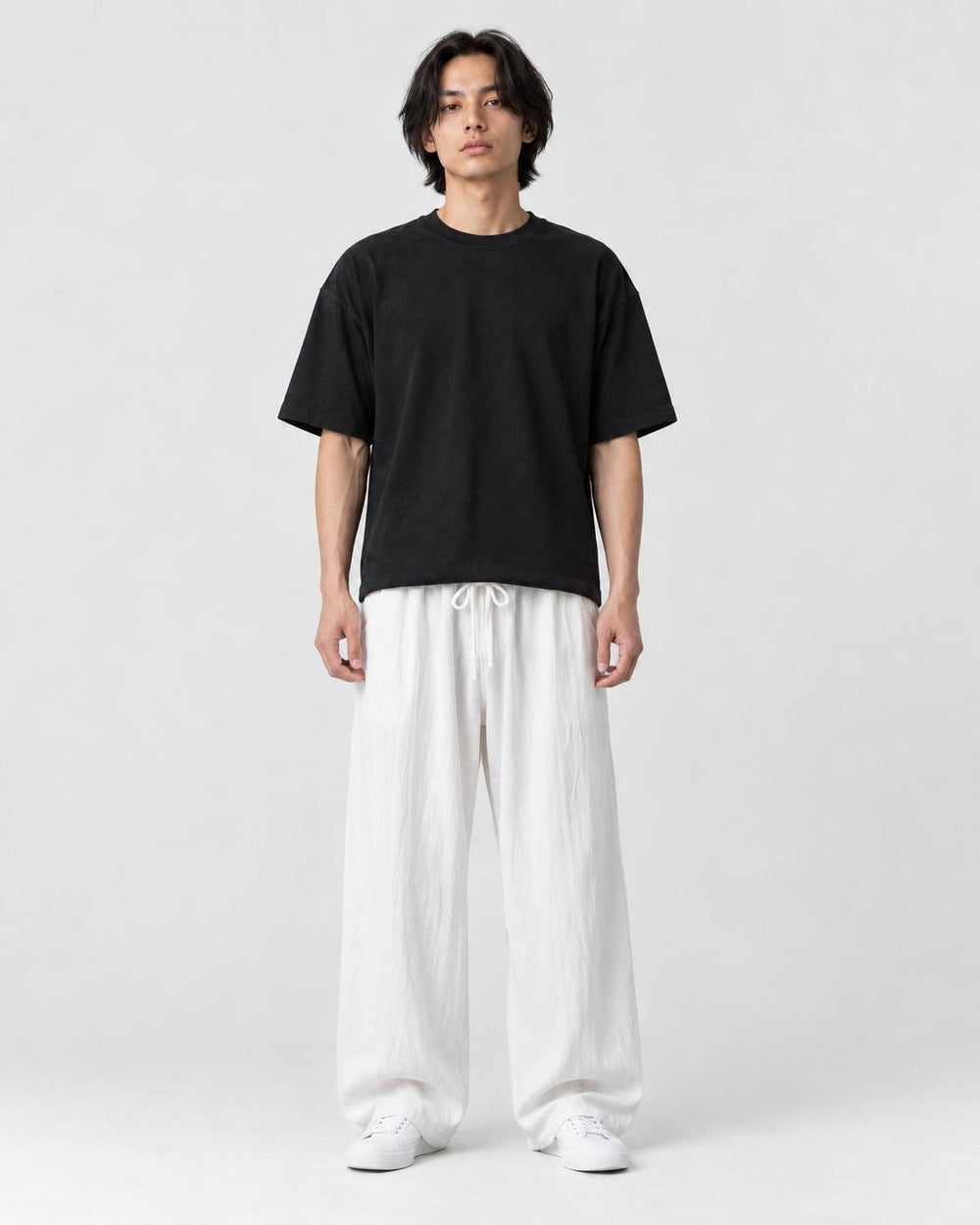 Model wearing the white wide-leg linen pants with a black tee and white sneakers, front view