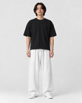 Model wearing the white wide-leg linen pants with a black tee and white sneakers, front view