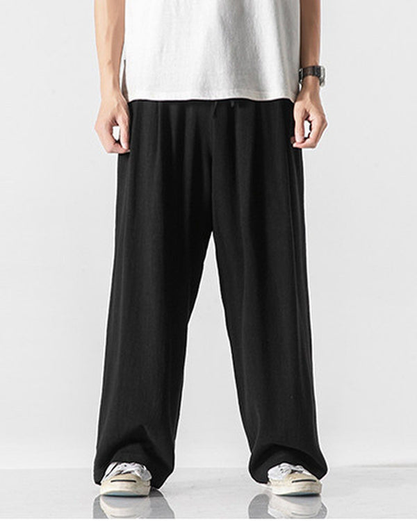 Black wide-leg linen pants with an elastic waist, worn with a white tee and canvas sneakers