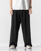 Black wide-leg linen pants with an elastic waist, worn with a white tee and canvas sneakers