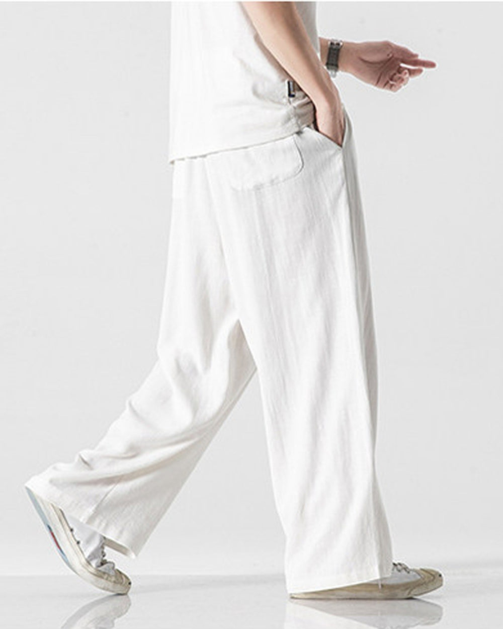 White wide-leg linen pants in motion, showing the long straight leg and a slanted side pocket