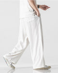 White wide-leg linen pants in motion, showing the long straight leg and a slanted side pocket