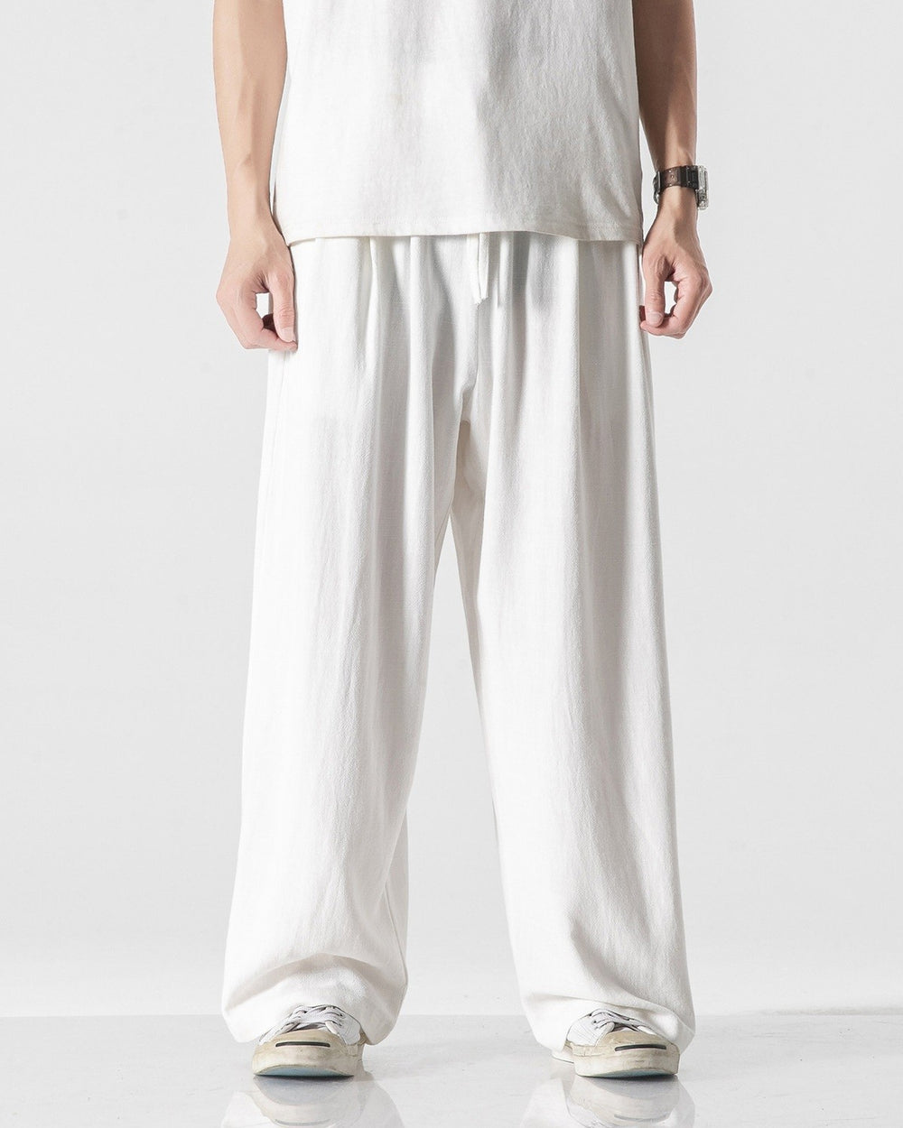 White wide-leg linen pants with an elastic drawcord waist, worn with a white tee and canvas sneakers