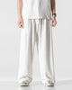White wide-leg linen pants with an elastic drawcord waist, worn with a white tee and canvas sneakers