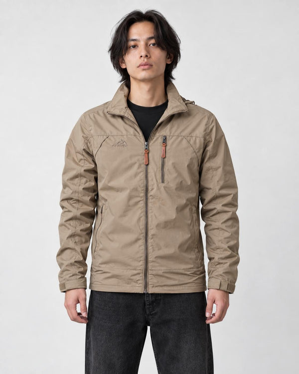 Model wearing the khaki windbreaker jacket over a black tee with black jeans and white sneakers, three-quarter crop