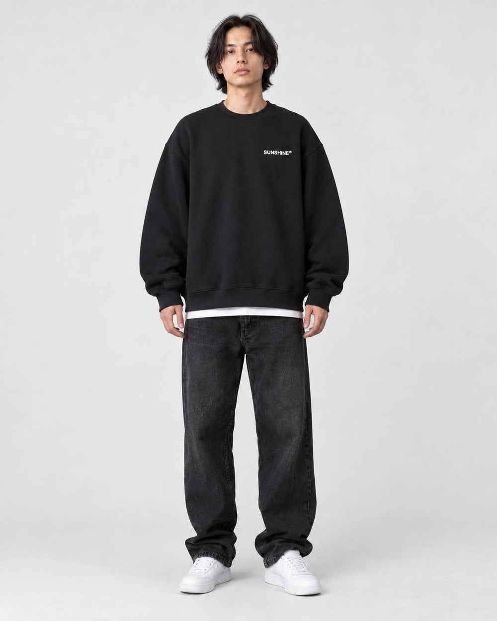 Model wearing the black sweatshirt with a small white chest print, front view