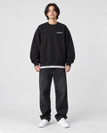 Model wearing the black sweatshirt with a small white chest print, front view