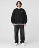 Model wearing the black sweatshirt with a small white chest print, front view