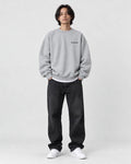 Model wearing the light gray sweatshirt with a small black chest print