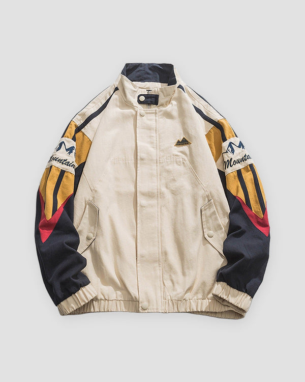 Beige color block jacket, front view, embroidered mountain sleeves in navy, mustard and red
