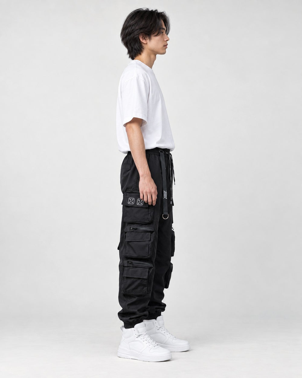 Model wearing the black multi-pocket techwear cargo pants, side view of the stacked thigh pockets