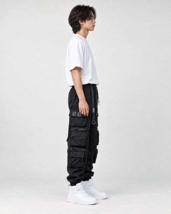 Model wearing the black multi-pocket techwear cargo pants, side view of the stacked thigh pockets