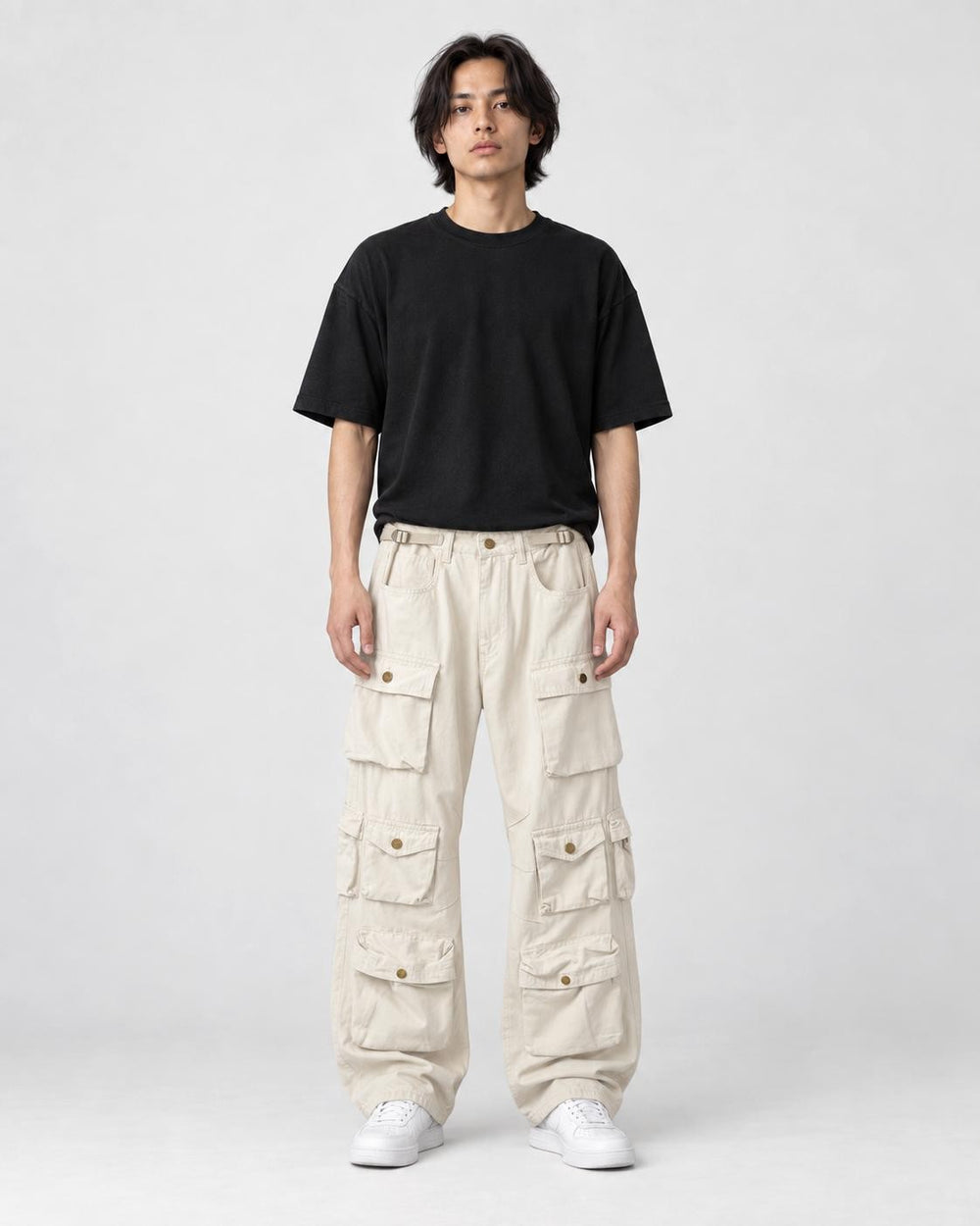 Model wearing the beige multi-pocket cargo pants with a black tee, front view