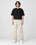 Model wearing the beige multi-pocket cargo pants with a black tee, front view