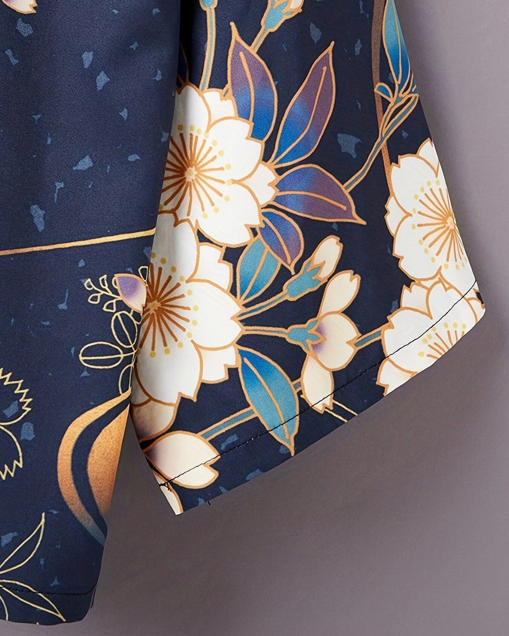 Close view of cream cherry blossoms and blue leaves outlined in gold at the haori sleeve