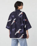 Man in the dark navy haori seen from behind at an angle, printed with white cranes and lilac flowers, over a white tee