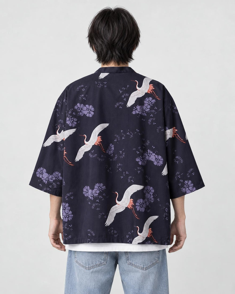 Man seen from behind in the dark navy haori printed with white cranes and lilac flowers, over a white tee