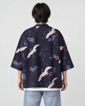 Man seen from behind in the dark navy haori printed with white cranes and lilac flowers, over a white tee