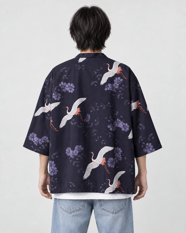 Man seen from behind in the dark navy haori printed with white cranes and lilac flowers, over a white tee