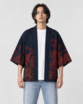 Man in the open dark navy haori with red-brown ink scenes on the front panels, a white tee and light jeans
