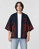 Man in the open dark navy haori with red-brown ink scenes on the front panels, a white tee and light jeans
