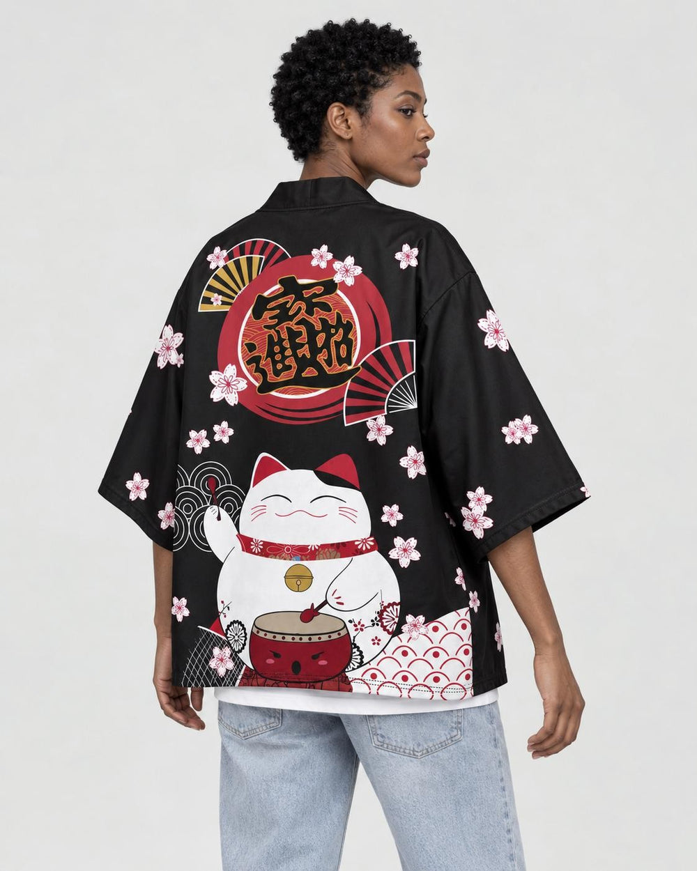 Woman in the black lucky-cat haori seen from behind at an angle, with blossoms on the sleeve