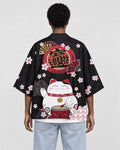 Woman seen from behind in a black haori with a white lucky cat, a red drum and cherry blossoms on the back