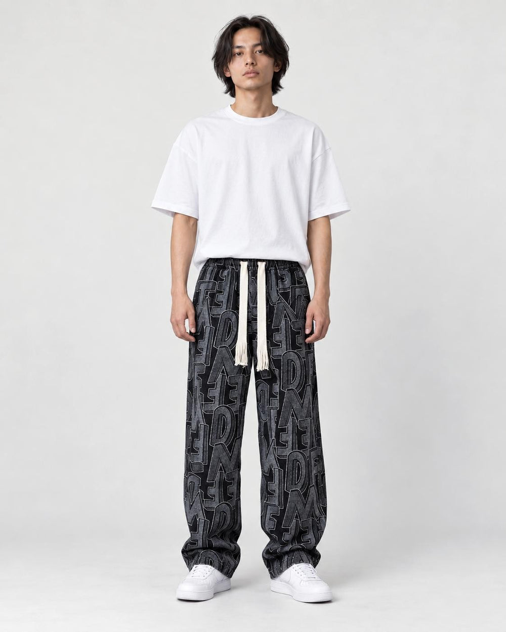 Model wearing the black outline letter corduroy pants with a black tee, front view