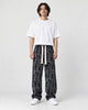 Model wearing the black outline letter corduroy pants with a black tee, front view