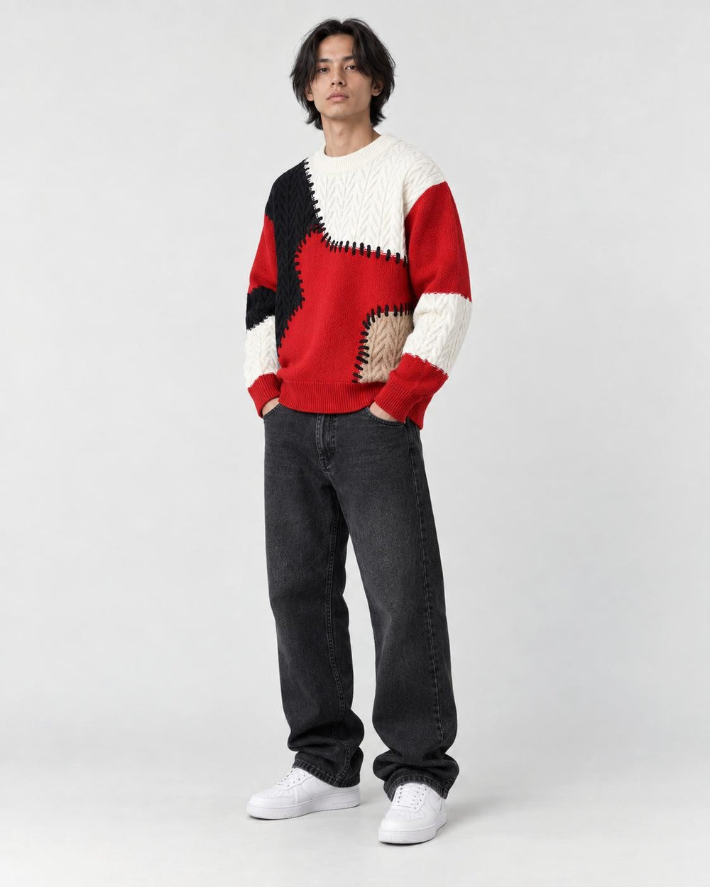 Model wearing the red patchwork cable knit sweater, three-quarter view