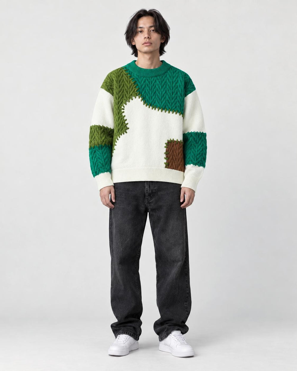 Model wearing the green patchwork cable knit sweater with jeans, front view