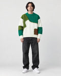 Model wearing the green patchwork cable knit sweater with jeans, front view