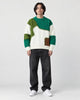 Model wearing the green patchwork cable knit sweater with jeans, front view