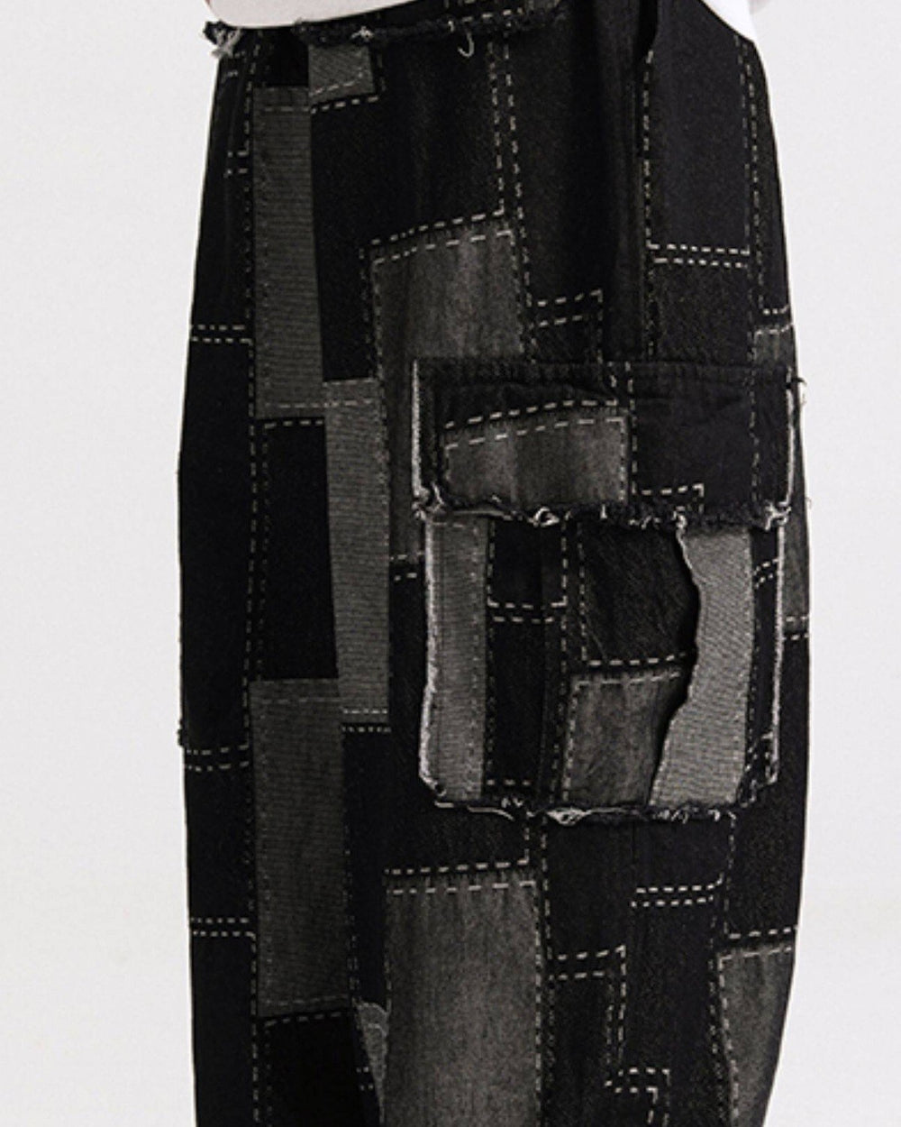 Close view of the black cargo pants with a raw-edged flap pocket and gray patches stitched in white