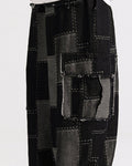 Close view of the black cargo pants with a raw-edged flap pocket and gray patches stitched in white