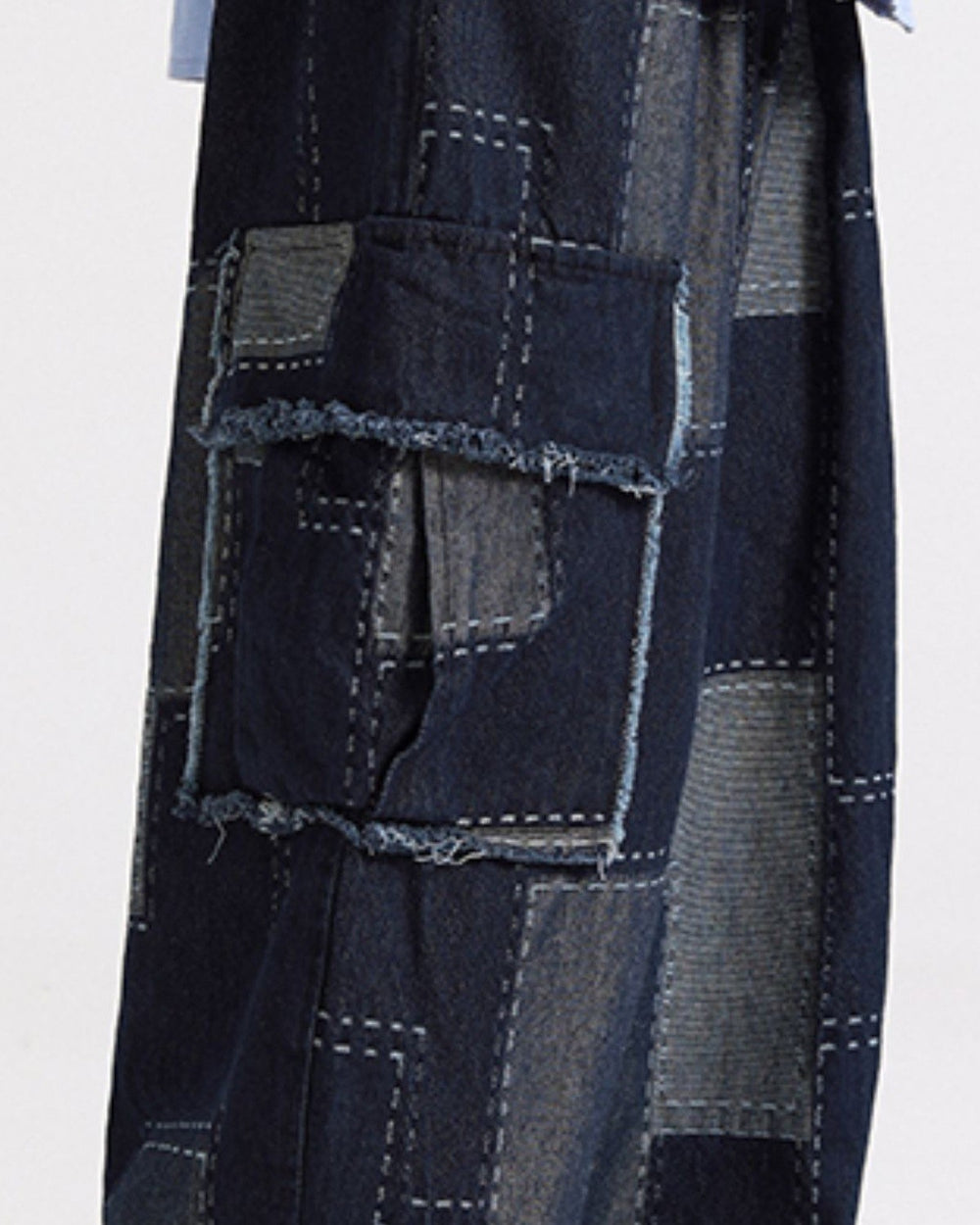 Close view of the raw-edged flap pocket and gray-blue patches on the indigo cargo pants