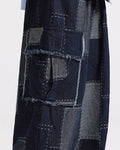 Close view of the raw-edged flap pocket and gray-blue patches on the indigo cargo pants