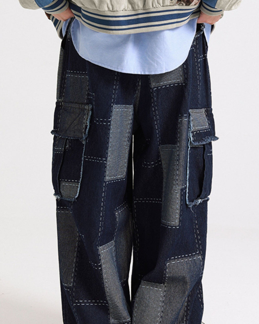 Wide-leg patchwork denim cargo pants in indigo with gray-blue patches and raw-edged flap pockets, front view