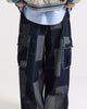 Wide-leg patchwork denim cargo pants in indigo with gray-blue patches and raw-edged flap pockets, front view