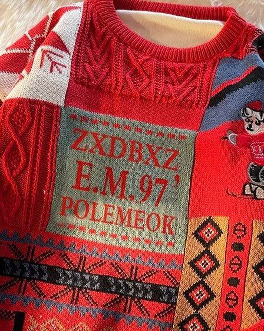 Close-up of the lettered patch and cartoon figure on the red patchwork sweater