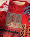 Close-up of the lettered patch and cartoon figure on the red patchwork sweater