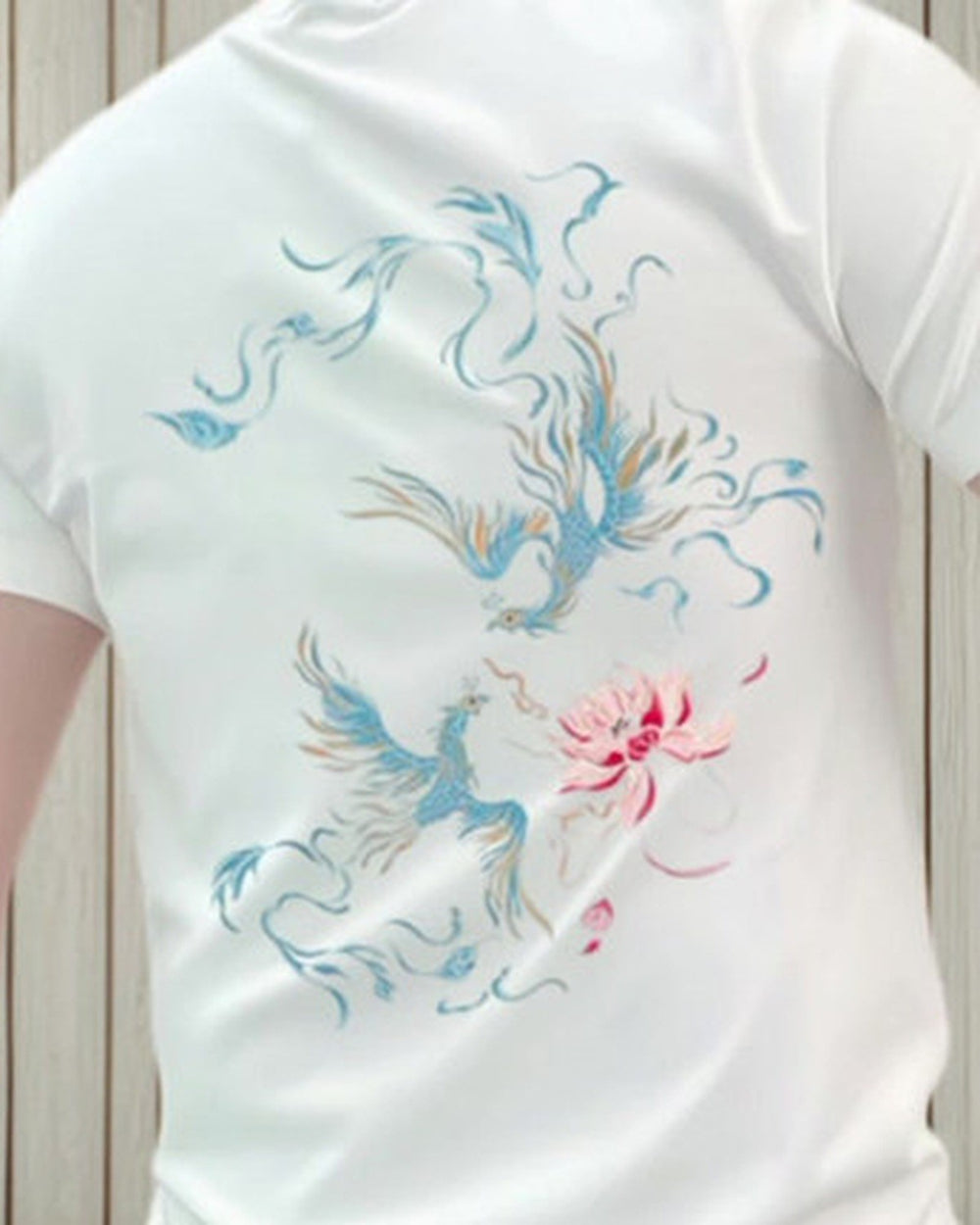 Close-up of the pale blue phoenixes and pink lotus printed on the back of the white tee
