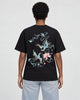 Model wearing the black phoenix and lotus print T-shirt with light-wash jeans, back view