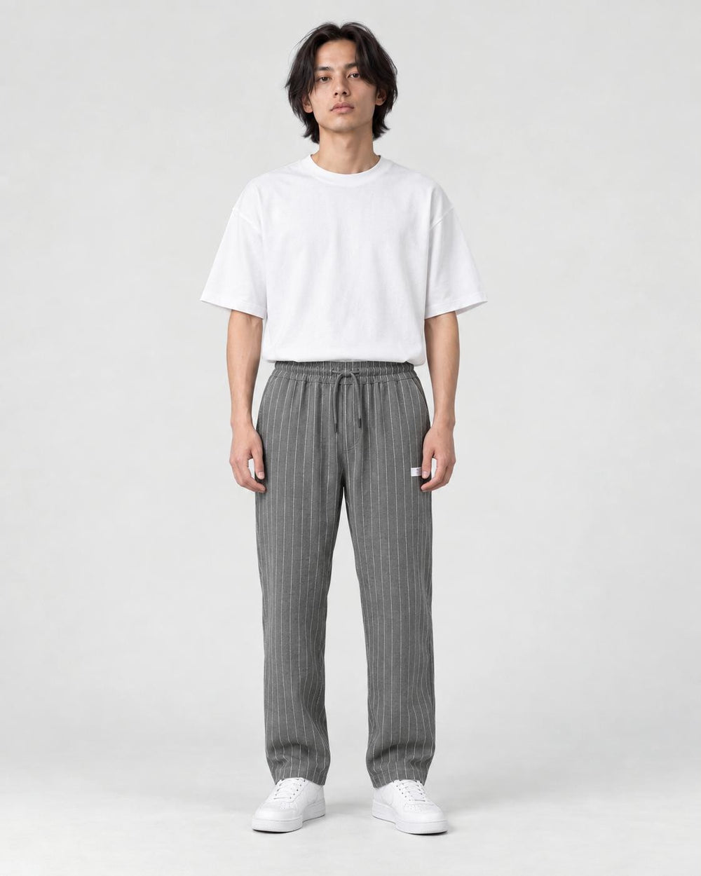 Model wearing the gray pinstripe drawstring pants with a white tee, front view