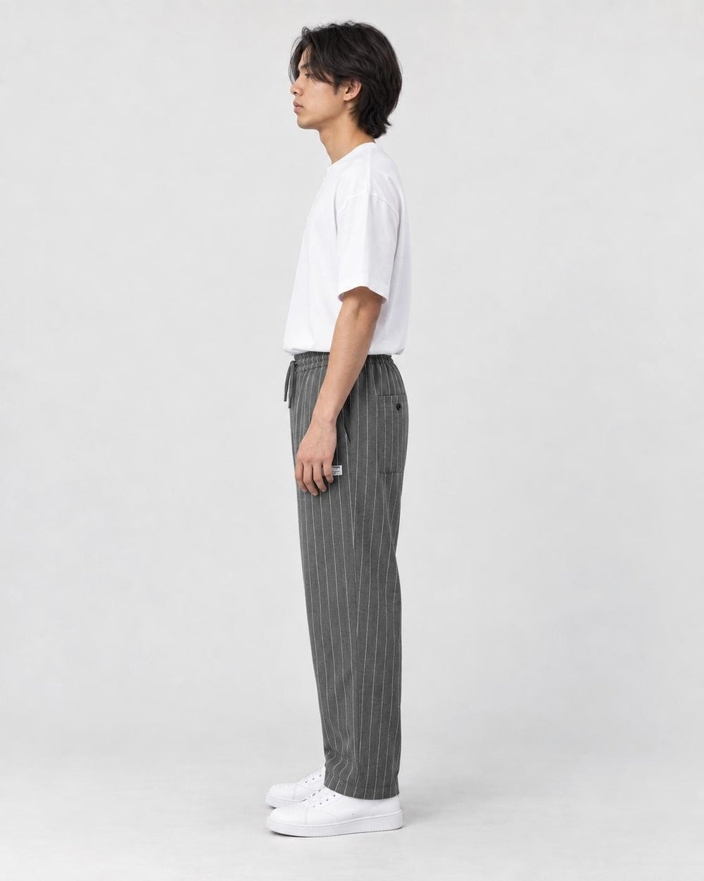Model wearing the gray pinstripe drawstring pants, side view