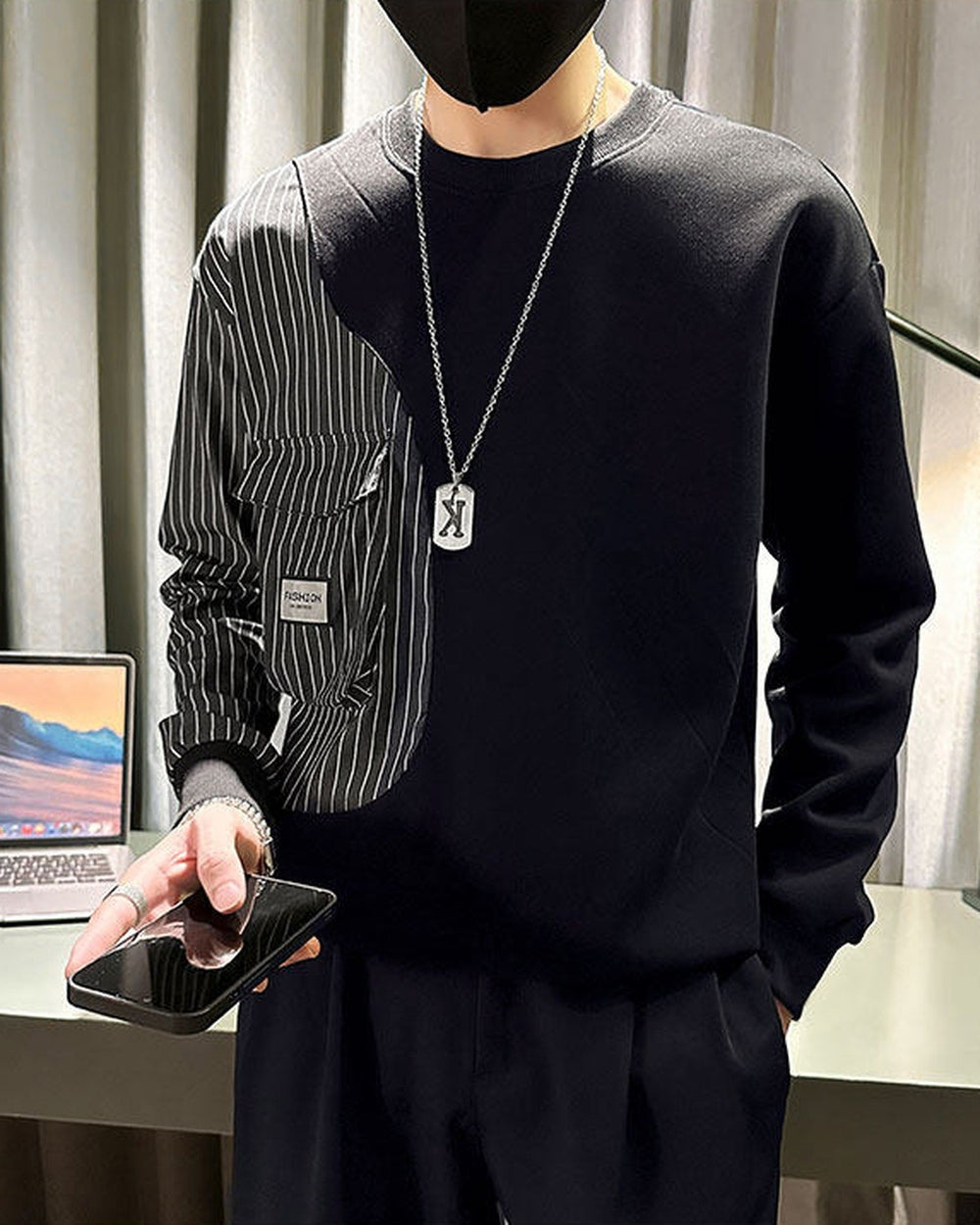 Close view of the black sweatshirt's pinstripe panel, flap pockets and small woven label