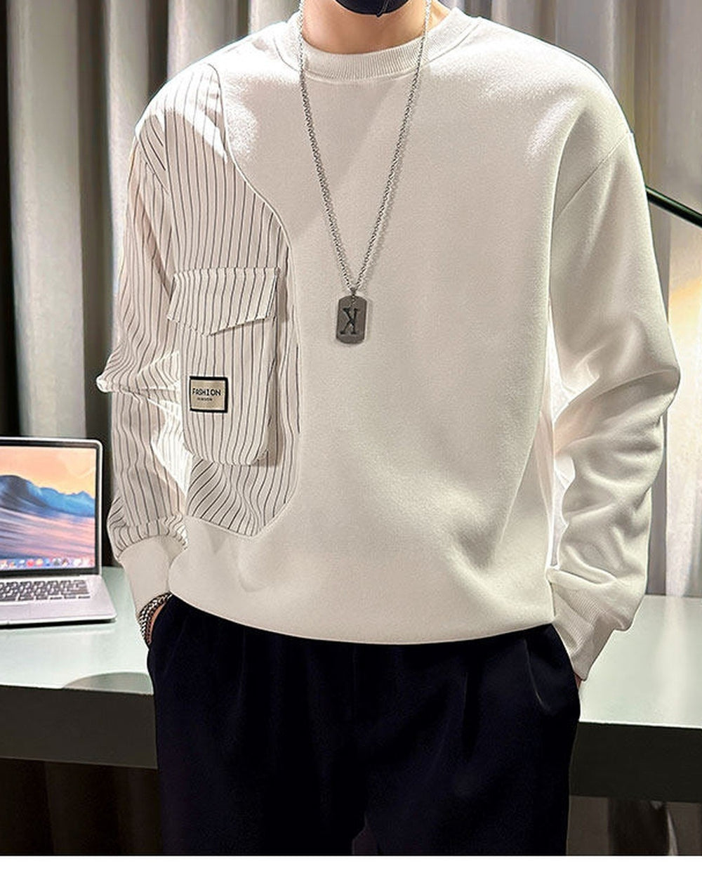 White crewneck sweatshirt with a pinstripe panel down the right sleeve and two flap pockets, worn with black trousers