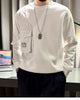 White crewneck sweatshirt with a pinstripe panel down the right sleeve and two flap pockets, worn with black trousers